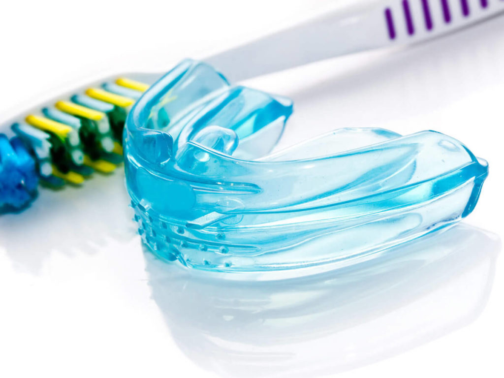 a blue mouthguard and a toothbrush