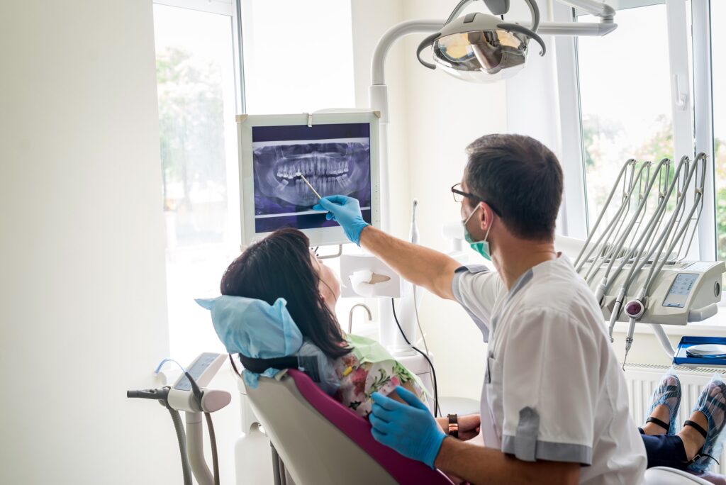 a dentist showing a patient her digital x-rays on a computer screen